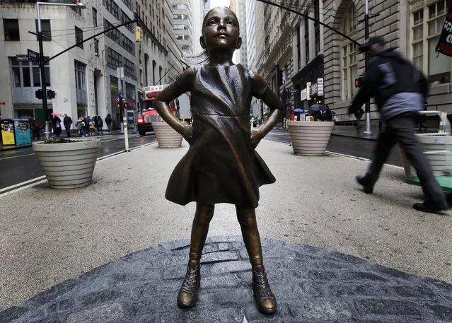 People walk past the sculpture 'The Fearless Girl' by US artist Kristen Visbal which was installed overnight facing the famous sculpture of the charging bull in Lower Manhattan by State Street Global Advisors to promote the idea of women in leadership positions in New York, New York, USA, 07 March 2017. (Photo by Justin Lane/EPA/EFE)