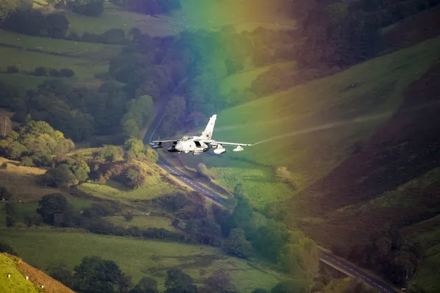 The plane flys through the rainbow in Wales. (Photo by Caters News Agency)