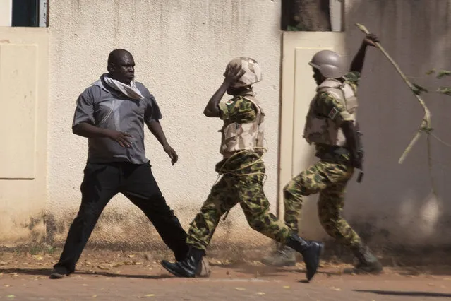 Soldiers hit an anti-government protester with a stick in Ouagadougou, capital of Burkina Faso, October 30, 2014. (Photo by Joe Penney/Reuters)