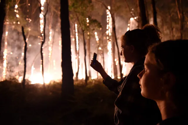 Locals watch a spot bush fire burn near their property in Benloch north of Melbourne, Australia, late 06 October 2015. Unseasonal hot temperature and winds sparked dozens of bushfires across Victoria.  Some 190 homes were threatened by bushfires out of control in the Australian state of Victoria with one home destroyed, authorities and news reports said. One of the biggest fires was started by rural fire brigades as a controlled burn two days ago about 80 kilometres north of Melbourne. (Photo by Tracey Nearmey/EPA)