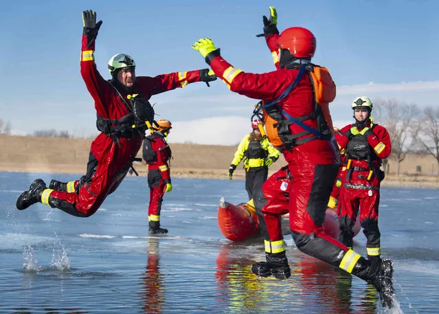 Waverly Fire's Tell Hanes, left, and Southeast Fire's Trey Wayne, right, jump over freezing water to high five while participating in a Surface Ice rescue technician course on Friday, January 6, 2023, at Holmes Lake Park in Lincoln, Neb. The International Rescue and Relief department at Union college held rescue training course at Holmes Lake for students and local fire departments. (Photo by Kenneth Ferriera/Lincoln Journal Star via AP Photo)