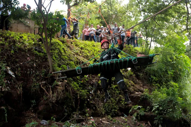 A Nicaraguan army member assists a participant playing the role of a victim during a national multi-hazard drill organized by the National System for Prevention, Mitigation and Attention to Disasters (SINAPRED), in the 30 de Mayo neighborhood in Managua, Nicaragua, September 26, 2016. (Photo by Oswaldo Rivas/Reuters)