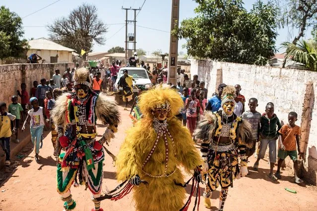 Men wearing the Simba mask, a famous Seneglese culture attire of handmade cloth, dance along the streets during the Kankurang Festival in Janjanbureh on January 28, 2023. The Kankurang Festival is a yearly event to showcase the unique cultural expression of the Kankurang and other traditions of West Africa. (Photo by Muhamadou Bittaye/AFP Photo)