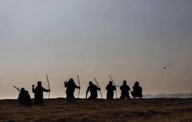A group of local archers are silhouetted against the afternoon sun on a ridge overlooking the Laitlum Canyon about 20km (12 miles) from Shillong, India, Sunday, January 22, 2023. In villages scattered across the northeastern Indian state of Meghalaya an ancient tradition of archery still continues and regular competitions are held between different localities. (Photo by Ashwini Bhatia/AP Photo)