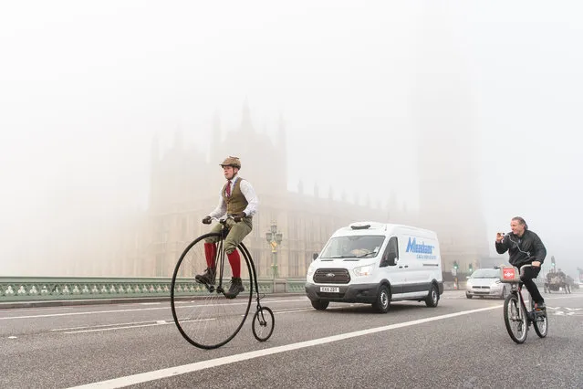A man rides a Penny Farthing bicycle past the Houses of Parliament in Westminster shortly after beginning the 119th "Veteran Car Run" from Hyde Park in London, to Brighton in southern England, on November 1, 2015. Around 500 classic cars took part in the 60 mile journey to the south coast resort. (Photo by Leon Neal/AFP Photo)