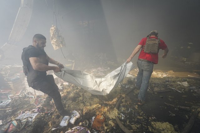 Rescuers carry a body after a Russian missile hit a large printing house in Kharkiv, Ukraine, Thursday, May 23, 2024. Russian missiles slammed into Ukraine’s second-largest city in the northeast of the country and killed at least seven civilians early Thursday, officials said, as Kyiv’s army labored to hold off an intense cross-border offensive by the Kremlin’s larger and better-equipped forces. (Photo by Andrii Marienko/AP Photo)