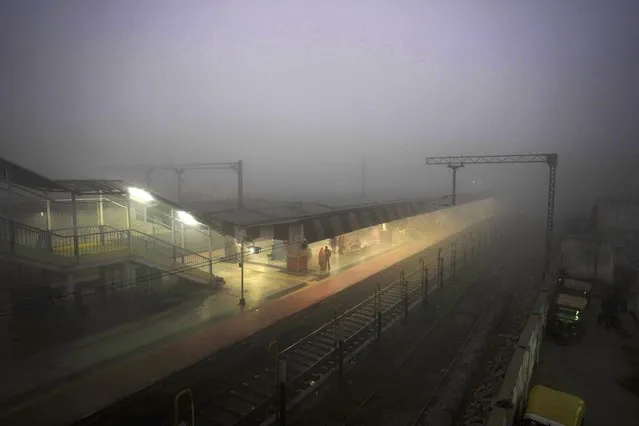 Passengers wait for their train amidst heavy morning fog in Varanasi, in the northern Indian state of Uttar Pradesh, Wednesday, December 21, 2022. North India is reeling under heavy fog, disrupting rail, road and air transport. (Photo by Rajesh Kumar Singh/AP Photo)