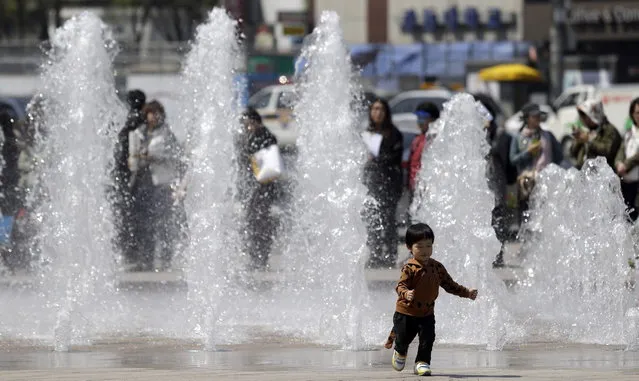 A South Korean boy runs away from a fountain during an environmental campaign as part of Earth Day celebrations in front of Seoul City Hall in Seoul, South Korea, Monday, April 22, 2013. (Photo by Lee Jin-man/AP Photo)