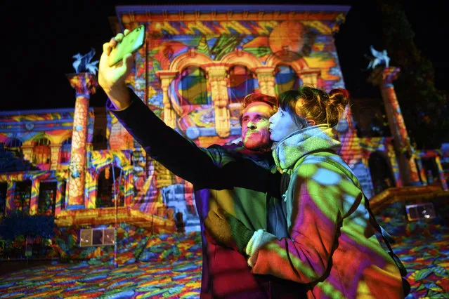 A couple takes a selfie in front of the light projection “Diving in the sea of colors” by the German light artist Daniel Margraf on the Palais de Rumine in the Place de la Riponne ahead of the Festival Lausanne Lumieres (Lausanne Light Festival), in Lausanne, Switzerland, 23 November 2020 (issued 24 November 2020). Eight projections on different buildings aiming to showcase the city of Lausanne under a new light will be on shows during the festival that runs from 24 November to 24 December 2020. (Photo by Laurent Gillieron/EPA/EFE)