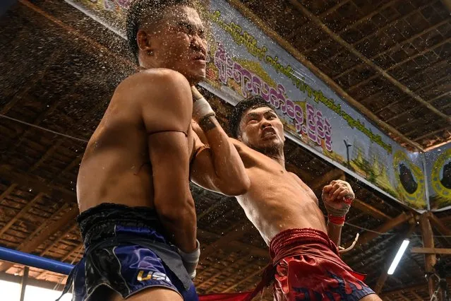 This photo taken on March 5, 2023 show fighters competing in a bout during a traditional Myanmar boxing Lethwei tournament at Pyi Thar Lin Aye pagoda in Hlaingbwe township in Karen state. The spectacle of almost-no-holds-barred traditional Myanmar boxing known as Lethwei, considered one of the most aggressive combat sports in the world – with fighters eschewing boxing gloves for thin gauze bandages wrapped around hardened knuckles – draws huge crowds in the eastern border state of Karen. (Photo by AFP Photo/Stringer)