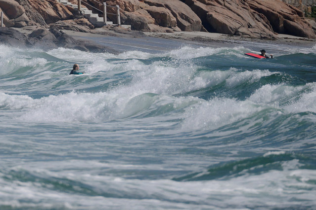 Surfers paddle in the water off Gloucester, Massachusetts, August 21, 2025. The National Weather Service has issued a high surf advisory for most of the New England coastline as Huricane Erin threatens to pound the shoreline with 6-to-20-foot waves. (Photo by Brian Snyder/Reuters)