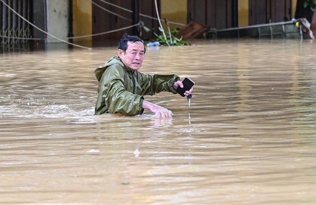 A man wades through a flooded street following heavy rains in Hoi An on October 30, 2025. Vietnam's coastal provinces have been lashed by heavy rains since October 26, with a record of up to 1.7 metres (five feet seven inches) falling over 24 hours. (Photo by Nhac Nguyen/AFP Photo)