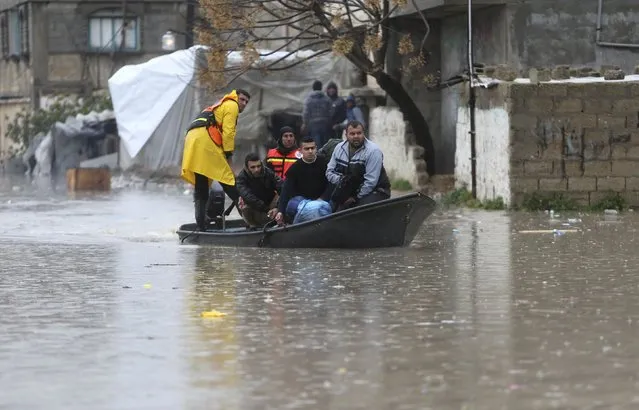 Members of Palestinian Civil Defence ride a boat as they evacuate people following heavy rain that flooded their houses in Rafah in the southern Gaza Strip January 9, 2015. Heavy rains and near-freezing temperatures in the approaching storm threatened to deepen the misery in the Gaza Strip. (Photo by Ibraheem Abu Mustafa/Reuters)