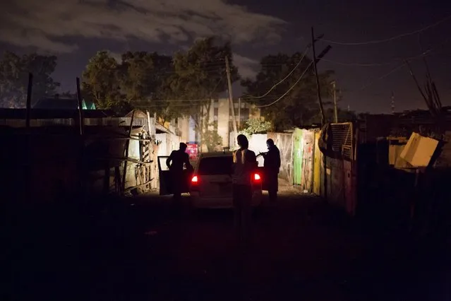 A man pleads with police officers to release a relative who they have just detained and placed in the boot of their vehicle in Dandora during a night patrol in Nairobi, Kenya, October 31, 2015. The man was chased and detained by officers after he tried to run away from the police when they asked him to approach the vehicle they were patrolling in. (Photo by Siegfried Modola/Reuters)