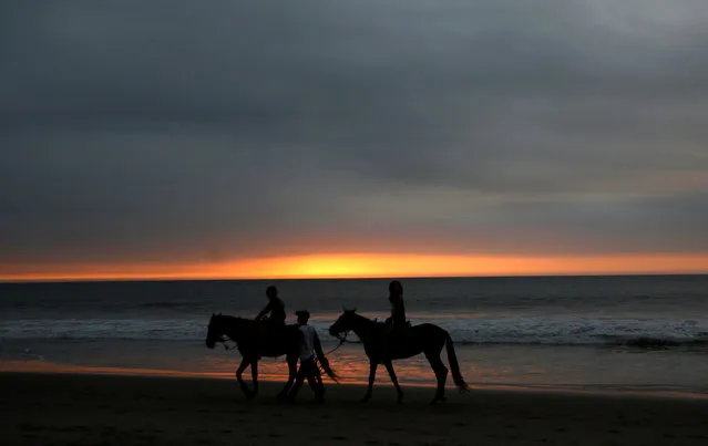 People riding horses by the shoreline of the tourist beach of Mancora in Piura,Peru, July 18, 2016. (Photo by Mariana Bazo/Reuters)