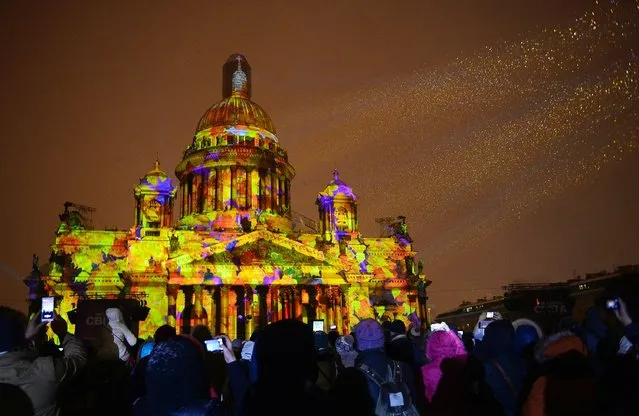 People watch a light show projected on the city's famed St. Isaac's Cathedral during the Festival of Lights in Saint Petersburg, on November 4, 2016. (Photo by Olga Maltseva/AFP Photo)