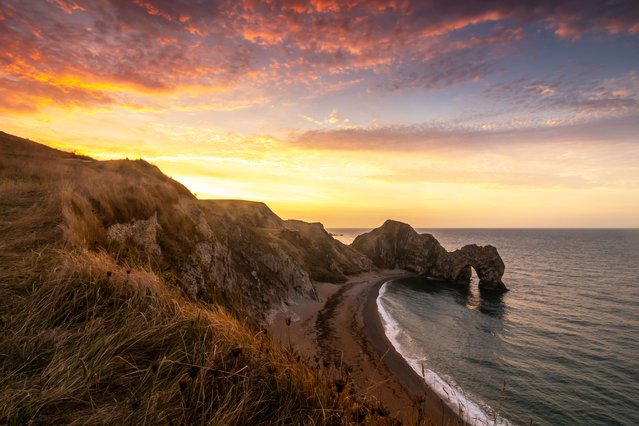 Sunrise at Durdle Door casts a golden hue over the natural limestone arch on the Jurassic Coast near Lulworth in Dorset, UK on September 7, 2025. (Photo by Rachel Baker/Bournemouth News)