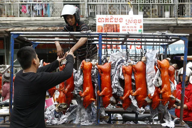 Street vendosr prepare grilled pigs to sell for the Chinese New Year celebrations at a market in Phnom Penh, Cambodia, 11 February 2021. Chinese people around the world celebrate the Lunar New Year, also known as the Spring Festival, which marks the year of the Ox. (Photo by Kith Serey/EPA/EFE)