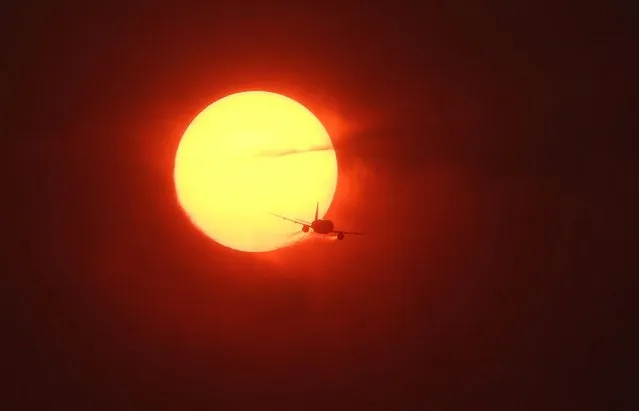 A commercial plane flies past a sun made dark orange by smoke from wildfires in Canada as seen from Washington, U.S., June 7, 2023. (Photo by Leah Millis/Reuters)