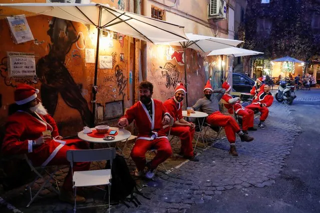 Men dressed in Santa suits sit in outdoor tables in Trastevere one day before Italy goes back to a complete lockdown as part of efforts put in place to curb the spread of the coronavirus disease (COVID-19), in Rome, Italy, December 23, 2020. (Photo by Remo Casilli/Reuters)