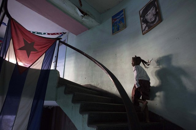 Sakia Corona, 8, passes a picture of Cuba's revolutionary hero Ernesto “Che” Guevara as she runs to a restroom during a rehearsal of a Contemporary Haitian dance in a communal center in downtown Havana, January 31, 2015. (Photo by Alexandre Meneghini/Reuters)