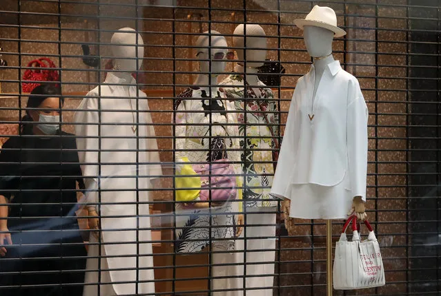 A woman wearing a face covering due to the COVID-19 pandemic decorates a shop window in London, Wednesday, February 17, 2021, as the lockdown continues. (Photo by Frank Augstein/AP Photo)