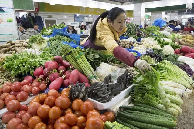 A vendor arranges vegetables at her stall at a market in Nanjing, Jiangsu province, China, December 9, 2015. China's consumer inflation picked up slightly in November rising 1.5 percent on-year from 1.3 percent in October. (Photo by Reuters/China Daily)