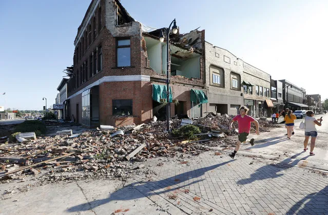 A local resident runs past a tornado-damaged building on Main Street, Thursday, July 19, 2018, in Marshalltown, Iowa. Several buildings were damaged by a tornado in the main business district in town including the historic courthouse. (Photo by Charlie Neibergall/AP Photo)