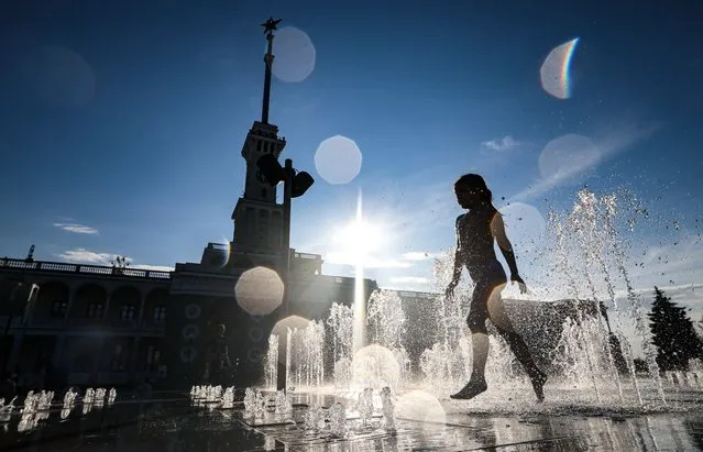 A girl plays with water in a ground fountain at Moscow's North River Terminal in Russia, Moscow on July 16, 2023. (Photo by Sergei Savostyanov/TASS)