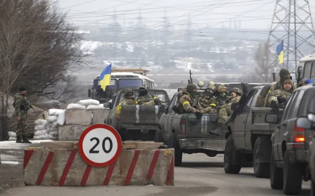Ukrainian government troops sit in the back of pick-up trucks as they pass a checkpoint near the town of Mariupol, Ukraine, Tuesday, February 10, 2015. The intense fighting, which the U.N. says has killed more than 5,300 people since April, comes ahead of a crucial summit including Western leaders on Wednesday as well as peace talks later Tuesday. (Photo by Petr David Josek/AP Photo)
