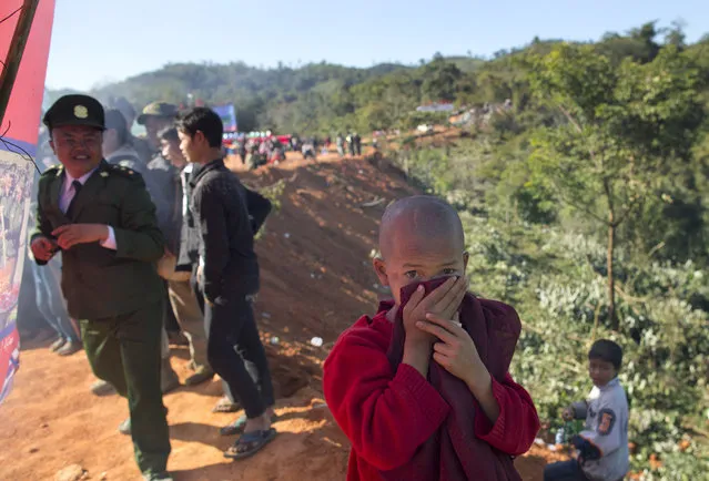 In this January 12, 2015 photo, a novice Buddhist monk covers his nose and mouth with his robe to protect himself from the smoke of burning narcotics during a ceremony in Mar Wong Village, northern Shan state, Myanmar, held by Ta’ang rebels. (Photo by Gemunu Amarasinghe/AP Photo)