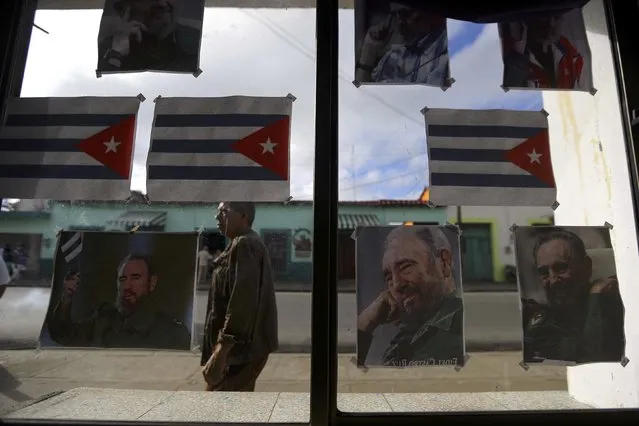 Cuban flags and images of Cuba's late President Fidel Castro hang on a store window as the town prepares for the arrival of the caravan carrying Castro's ashes in Guimaro, Cuba, December 1, 2016. (Photo by Ivan Alvarado/Reuters)
