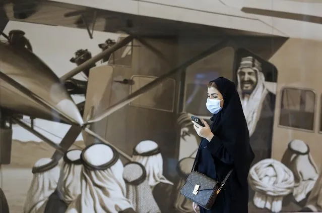 A Saudi passenger walks in front of an enlargement of an old photograph showing the late King Abdul Aziz Al Saud as he peers out of an airplane, at King Abdulaziz International Airport in Jiddah, Saudi Arabia, Monday, May 17, 2021. Vaccinated Saudis will be allowed to leave the kingdom for the first time in more than a year as the country eases a ban on international travel that had been in place to try and contain the spread of the coronavirus and its new variants. (Photo by Amr Nabil/AP Photo)