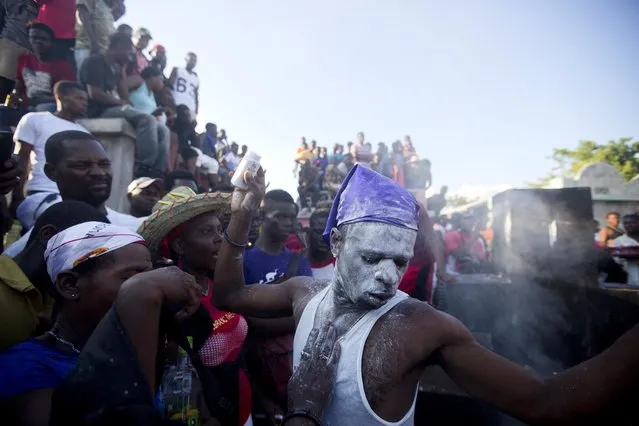 In this November 1, 2018 photo, voodoo believers who are supposed to be possessed with Gede spirit perform rituals in the middle of Baron Samedi's tomb during the annual Voodoo festival Fete Gede at Cite Soleil Cemetery in Port-au-Prince, Haiti. Every year, during the celebration, they paint their faces with white powder, wear the loas' clothes, travel the narrowly pathways through the shanty town and go to cemeteries to pay tribute to the spirits. (Photo by Dieu Nalio Chery/AP Photo)