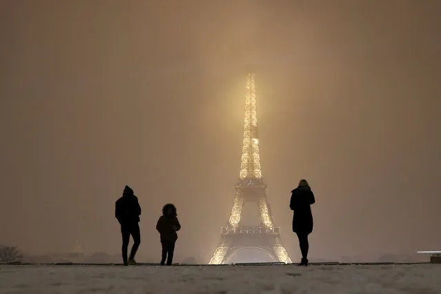 Tourists take pictures as they walk on a snow-covered path near the Eiffel Tower in Paris, as winter weather with snow and freezing temperatures arrive in France, February 6, 2018. (Photo by Gonzalo Fuentes/Reuters)