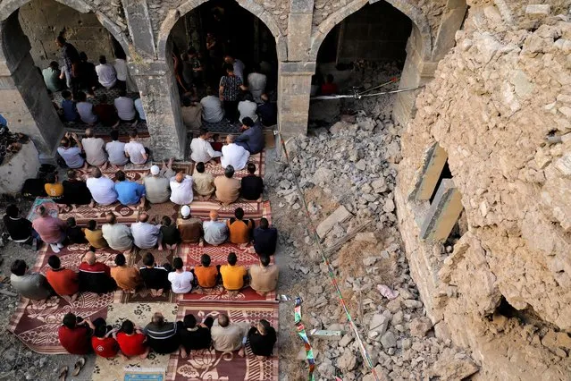 People attend Eid al-Fitr prayer marking the end of the holy fasting month of Ramadan, at the oldest Al-Masfi mosque, which was damaged during the war against Islamic State militants in Mosul, Iraq on May 13, 2021. (Photo by Abdullah Rashid/Reuters)