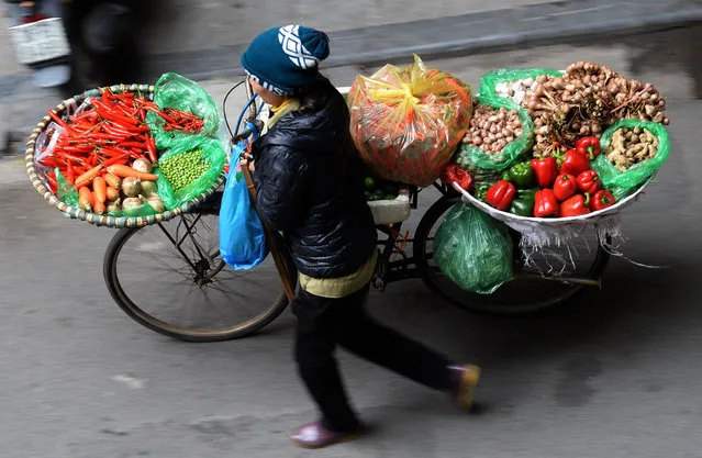 A vendor sells vegetables along a street in downtown Hanoi on February 4, 2016 as Vietnamese prepare to celebrate the Lunar New Year, or Tet. Vietnamese will mark the Lunar New Year, this year the Year of the Monkey in the Chinese Zodiac, along with many countries in east Asia, on February 8. (Photo by Hoang Dinh Nam/AFP Photo)