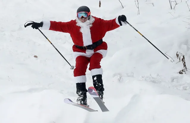 A skier dressed as Santa Claus takes flight during the annual Santa Sunday event, Sunday, December 2, 2018, in Newry, Maine. The red-suited lookalikes aim to put a smile on people’s faces while raising money for charity. (Photo by Robert F. Bukaty/AP Photo)