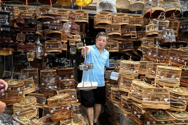 A bird cage vendor shows a bird rack to a customer at a pet market in Beijing on July 7, 2021. (Photo by Jade Gao/AFP Photo)