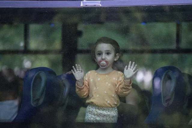 A young girl looks through a bus window as her family departs the northern Israeli city of Kiryat Shmona, Israel, Friday, October 20, 2023. The Israeli military announced Friday it would evacuate the border city a day after three residents were injured by cross-border fire from militants in Lebanon. (Photo by Baz Ratner/AP Photo)