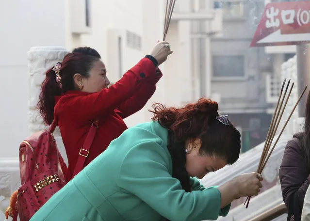 Visitors hold joss sticks as they offer prayer at a temple in China Town in Yokohama, near Tokyo, Monday, February 8, 2016.(Photo by Koji Sasahara/AP Photo)