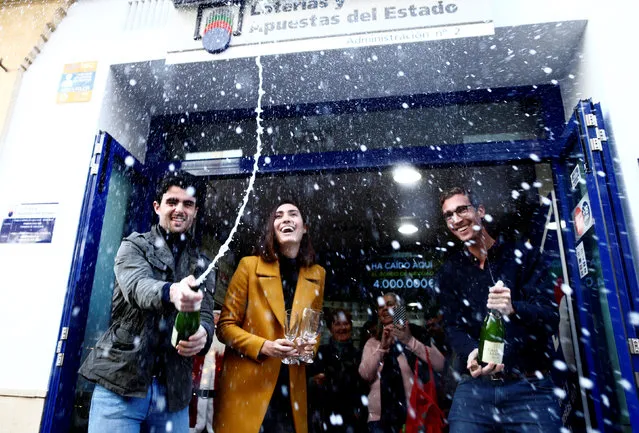 Kiosk owners Juan, Maria and Miguel Angel celebrate outside their kiosk, where the winning number was sold with the biggest prize of Spain's Christmas Lottery “El Gordo” (The Fat One), in Ronda, Spain December 22, 2018. (Photo by Jon Nazca/Reuters)