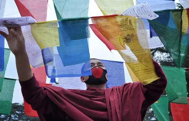 An exile Tibetan monk ties multi-color prayer flags called wind horse or lungta on a tall pole on the third day of the Tibetan New Year in Dharmsala, India, 11 February 2016. Tibetans believe that the Buddhist prayers printed on these flags of five colors representing the five elements, earth, fire, sky, water and air, are spread by wind. (Photo by Sanjay Baid/EPA)