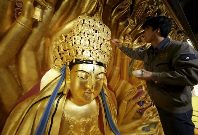 A worker paints as he restores the gold foil on the thousand-hands Bodhisattva in Chongqing Municipality, March 25, 2015. The restoration project which started 2008 draws to an end for the statue originally carved in the Southern Song Dynasty (1127-1279). (Photo by Reuters/China Daily)
