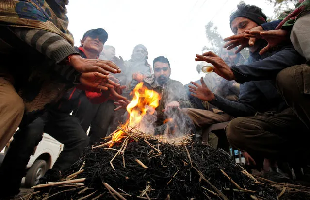People warm themselves by a fire on a cold winter morning in Chandigarh, India, December 31, 2016. (Photo by Ajay Verma/Reuters)