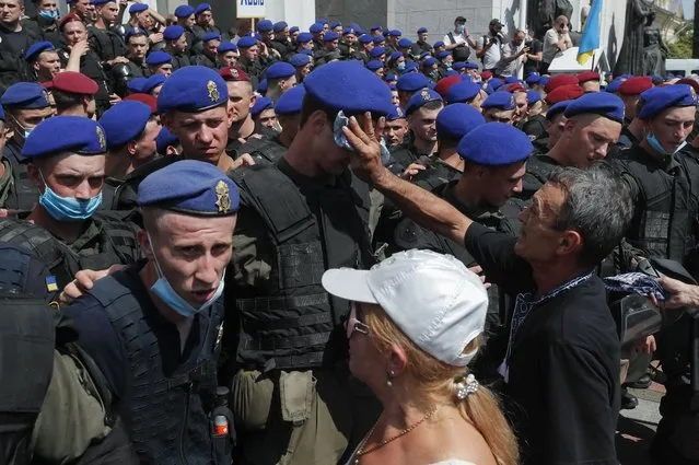 A protester, a former policeman, wipes young policeman's forehead from sweat during pensioners protest in front of the parliament building in Kiev, Ukraine, 14 July 2021. Pensioners of different power structures gathered in Kiev to demand recalculation and increasing their pensions. (Photo by Sergey Dolzhenko/EPA/EFE/Rex Features/Shutterstock)
