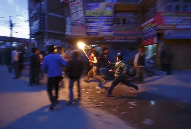 A protester tries to run from the riot police personnel (unseen) trying to stop the torch rally in Kathmandu April 6, 2015. (Photo by Navesh Chitrakar/Reuters)