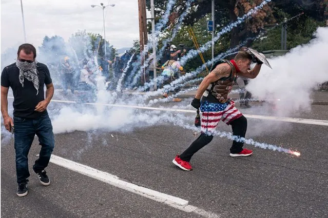 Far-right extremists react to an exploding firework thrown by left-wing counter protesters on August 22, 2021 in Portland, Oregon. The Proud Boys and other far-right extremists fought with anti-fascist activists in Portland on the anniversary of a similar fight in 2020. (Photo by Nathan Howard/Getty Images)