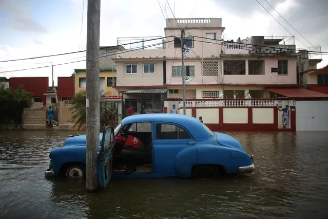A man tries to start the engine of a vintage car in a flooded street in Havana, Cuba, January 23, 2017. (Photo by Alexandre Meneghini/Reuters)
