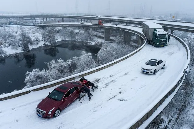 People push a car stuck on a highway following heavy snowfall in the region, during the Spring Festival travel rush ahead of the Chinese Lunar New Year, in Wuhan, Hubei province, China on February 6, 2024. (Photo by Reuters/China Daily)
